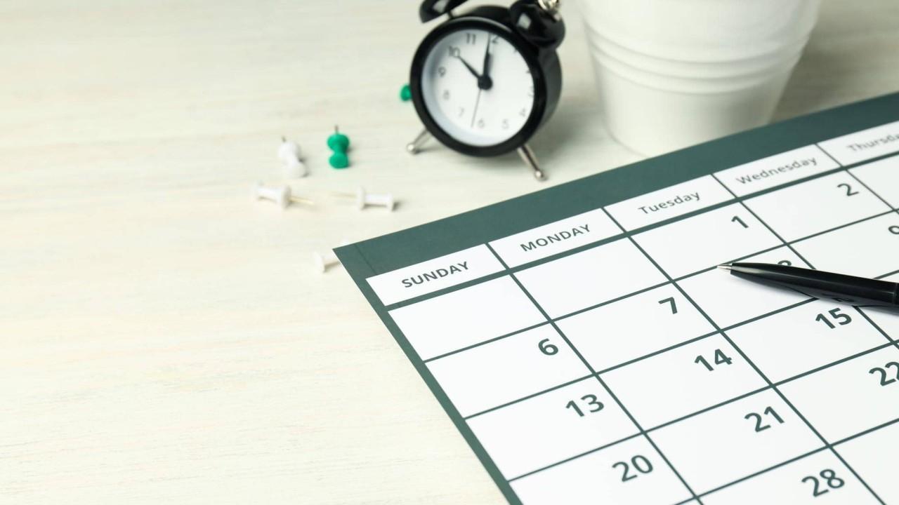 A paper schedule on a table next to an alarm clock